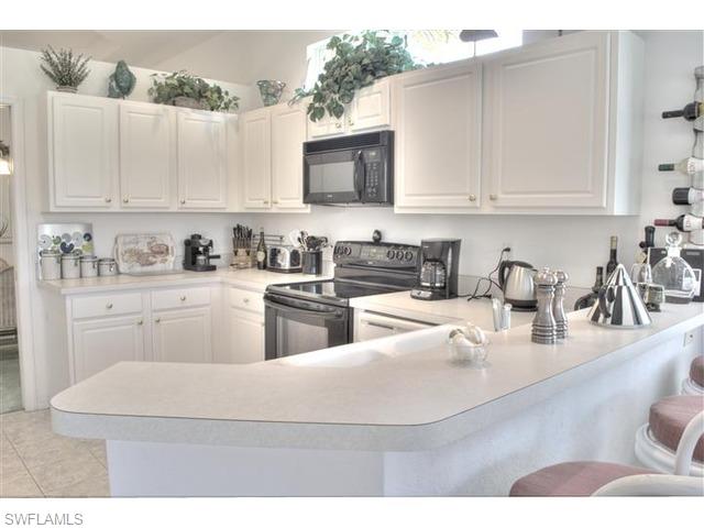 400 Harvard Court Naples, FL 34104 - Photo 4 of 16 a kitchen with stainless steel appliances granite countertop a sink a stove and white cabinets
