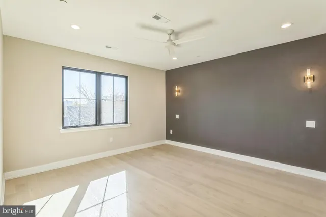 an empty room with windows and ceiling fan