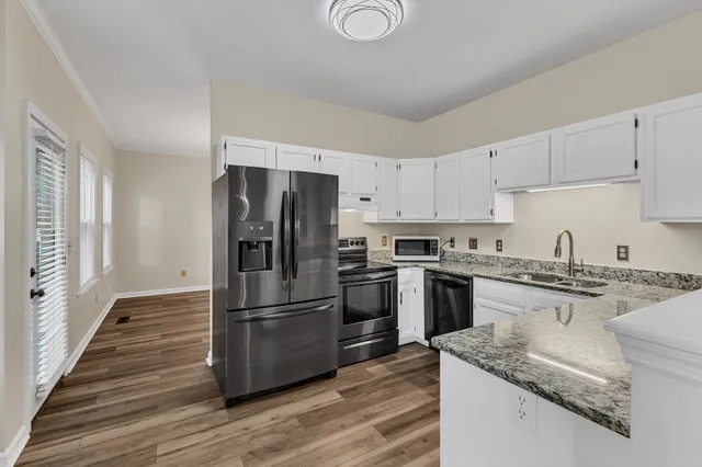 a kitchen with granite countertop stainless steel appliances a refrigerator a stove top oven and sink