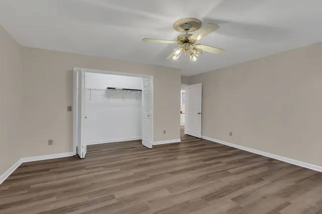 an empty room with wooden floor fan and windows