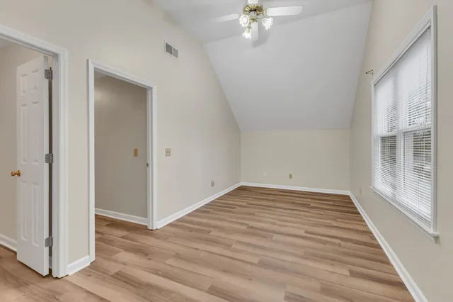 a view of an empty room with wooden floor and a window