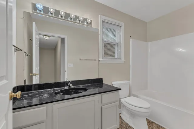 a bathroom with a granite countertop sink and a toilet