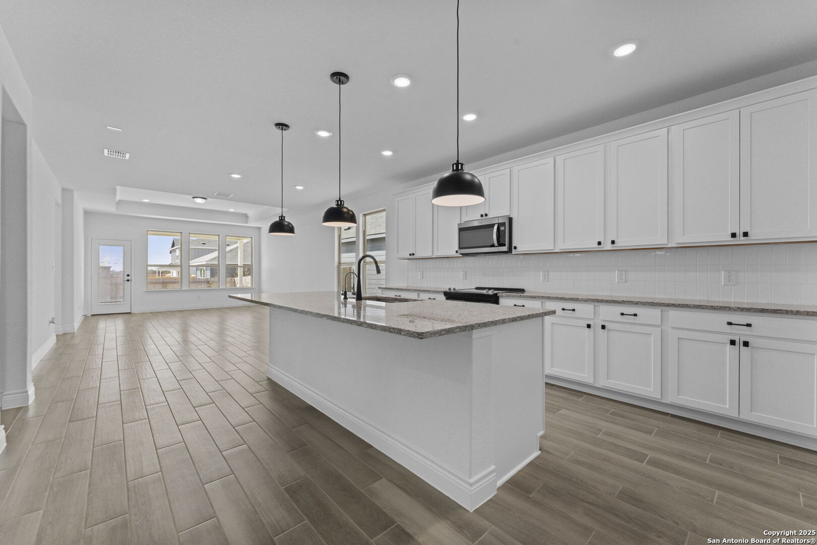 4014 Paddock Trail Seguin, TX 78155 - Photo 6 of 27 a large kitchen with stainless steel appliances granite countertop a stove a sink a refrigerator and white cabinets with wooden floor