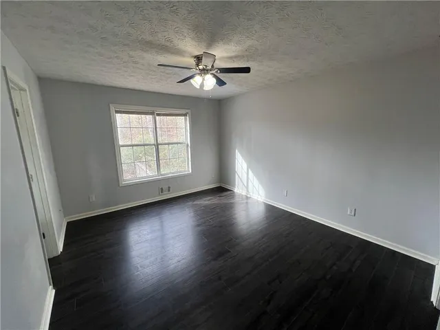 an empty room with wooden floor chandelier fan and windows