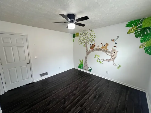 an empty room with wooden floor and potted plant