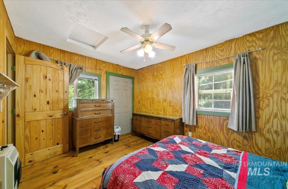 221 Tollgate Road Boise, ID 83716 - Photo 14 of 32 Bedroom featuring wood walls, light wood finished floors, a textured ceiling, a ceiling fan, and heating unit