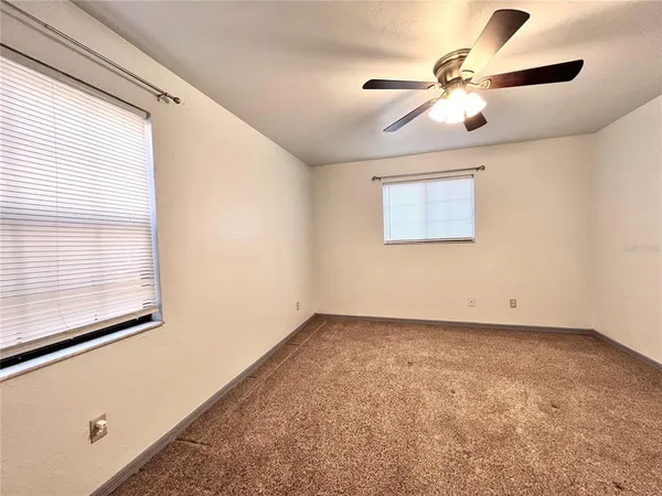 an empty room with windows and fan