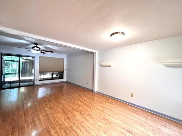 a view of an empty room with a window and wooden floor