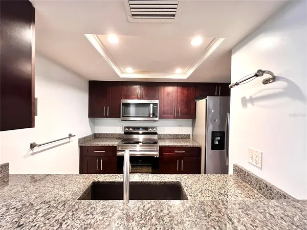 a kitchen with stainless steel appliances kitchen island granite countertop a refrigerator and a stove top oven