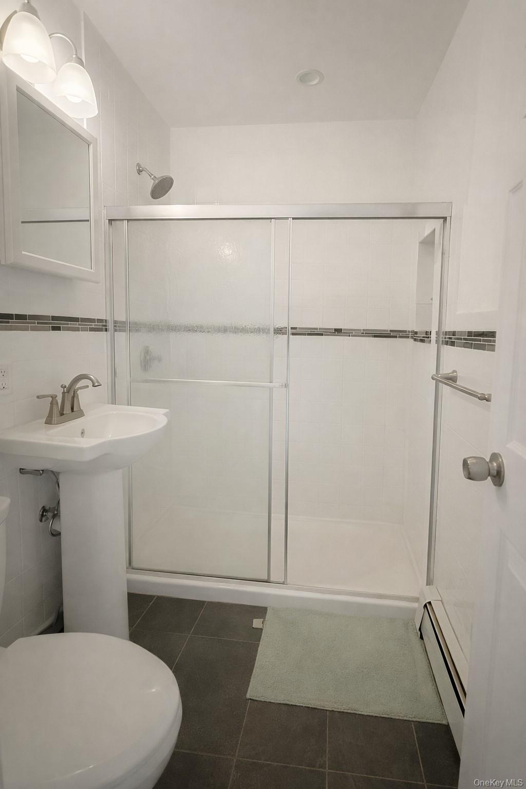 187 Horseblock Road Farmingville, NY 11738 - Photo 8 of 11 Bathroom with dark tile patterned floors, baseboard heating, and a stall shower