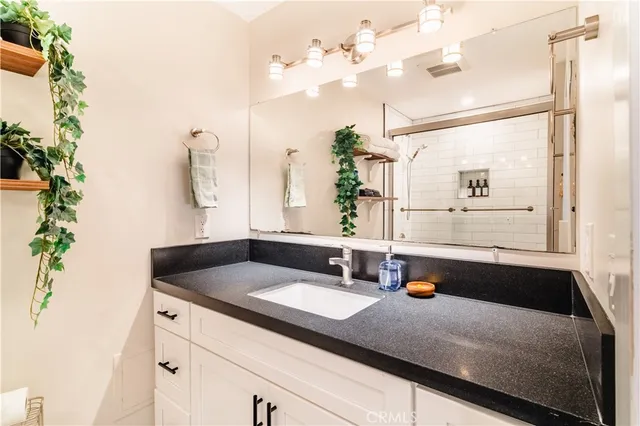 a bathroom with a granite countertop sink a toilet a mirror and shower