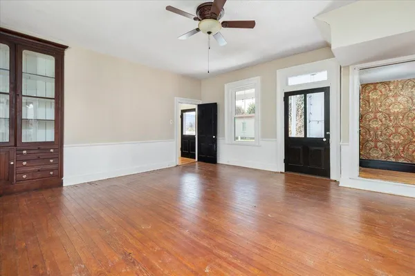 a view of an empty room with wooden floor fireplace and a window