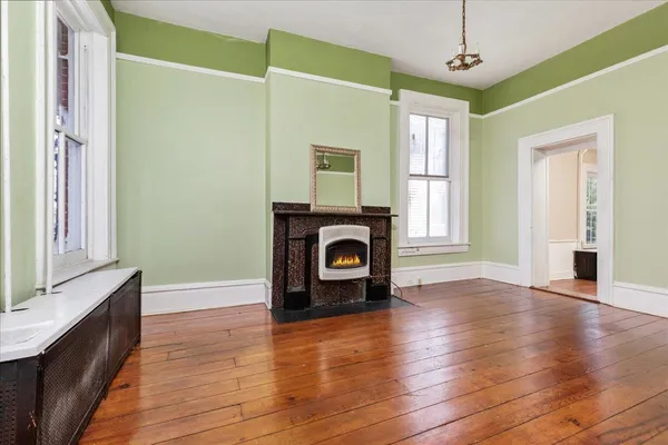 a view of a livingroom with a fireplace a ceiling fan and wooden floor