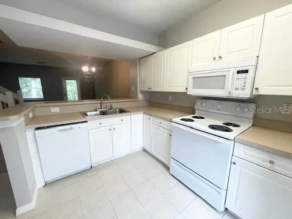 a kitchen with granite countertop white cabinets sink and white appliances
