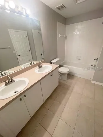 a spacious bathroom with a double vanity sink toilet mirror and shower