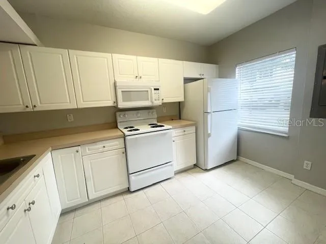 a kitchen with granite countertop white cabinets and white appliances