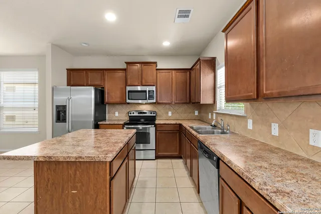 a kitchen with stainless steel appliances granite countertop a sink stove microwave and refrigerator