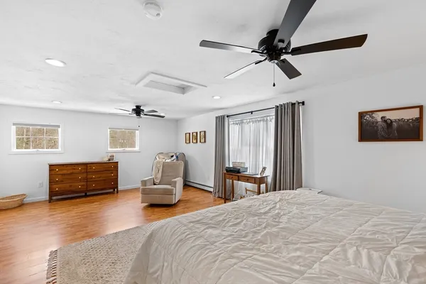 a bedroom with a bed dresser and wooden floor