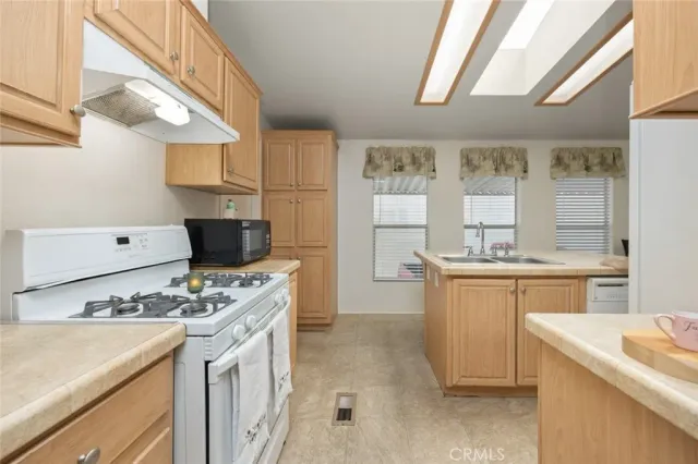 a kitchen that has a lot of white cabinets and stainless steel appliances