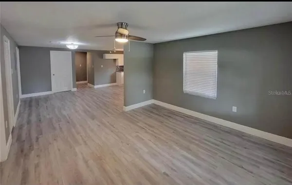 a view of an empty room with wooden floor and a window