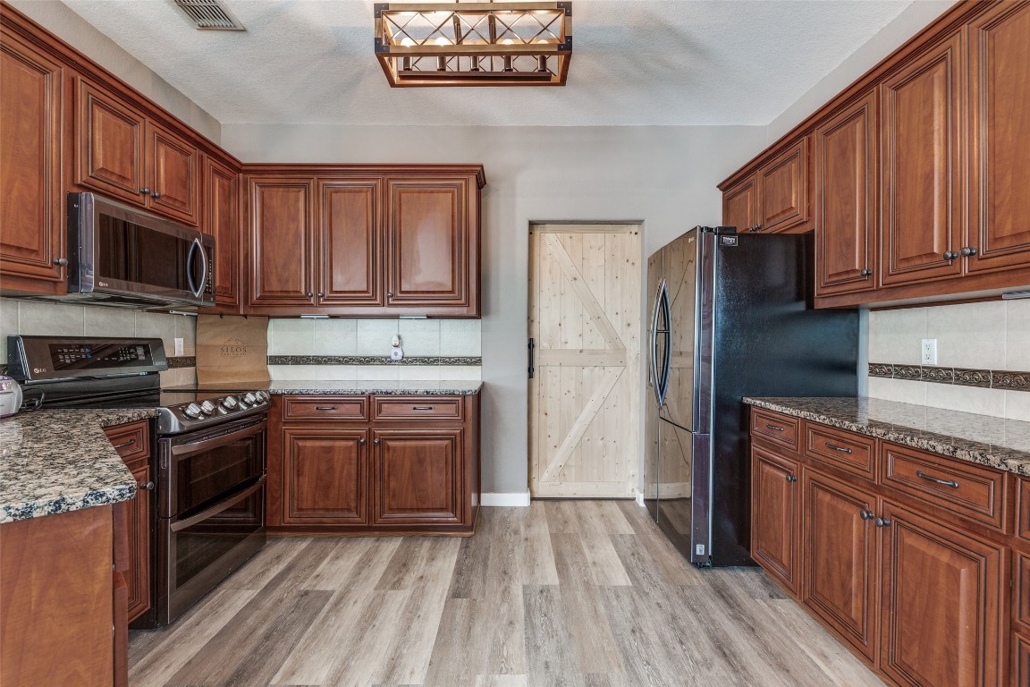 1536 Kings Ranch Road Bandera, TX 78003 - Photo 17 of 35 a kitchen with granite countertop wooden floors stainless steel appliances and a sink