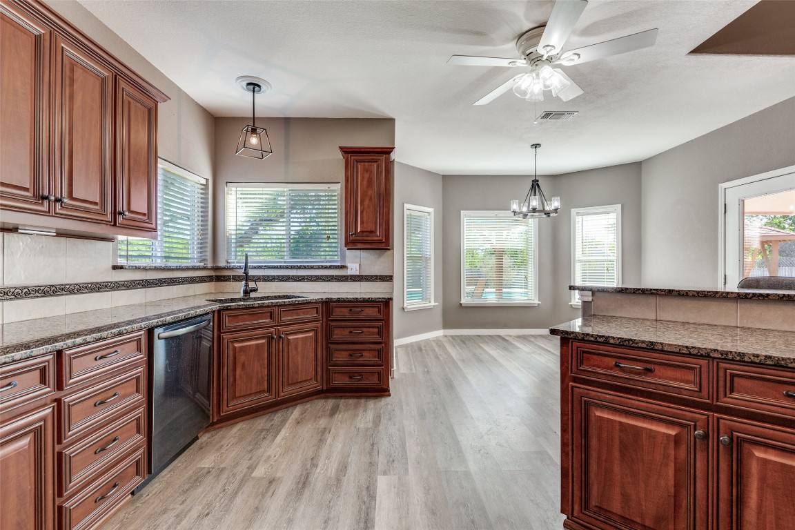 1536 Kings Ranch Road Bandera, TX 78003 - Photo 18 of 35 a large kitchen with granite countertop a stove top oven a sink dishwasher and wooden cabinets