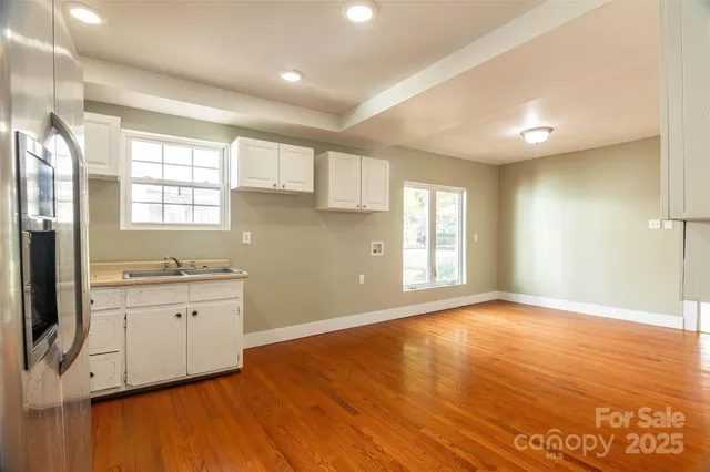 a kitchen with granite countertop a stove a sink wooden floor and cabinets