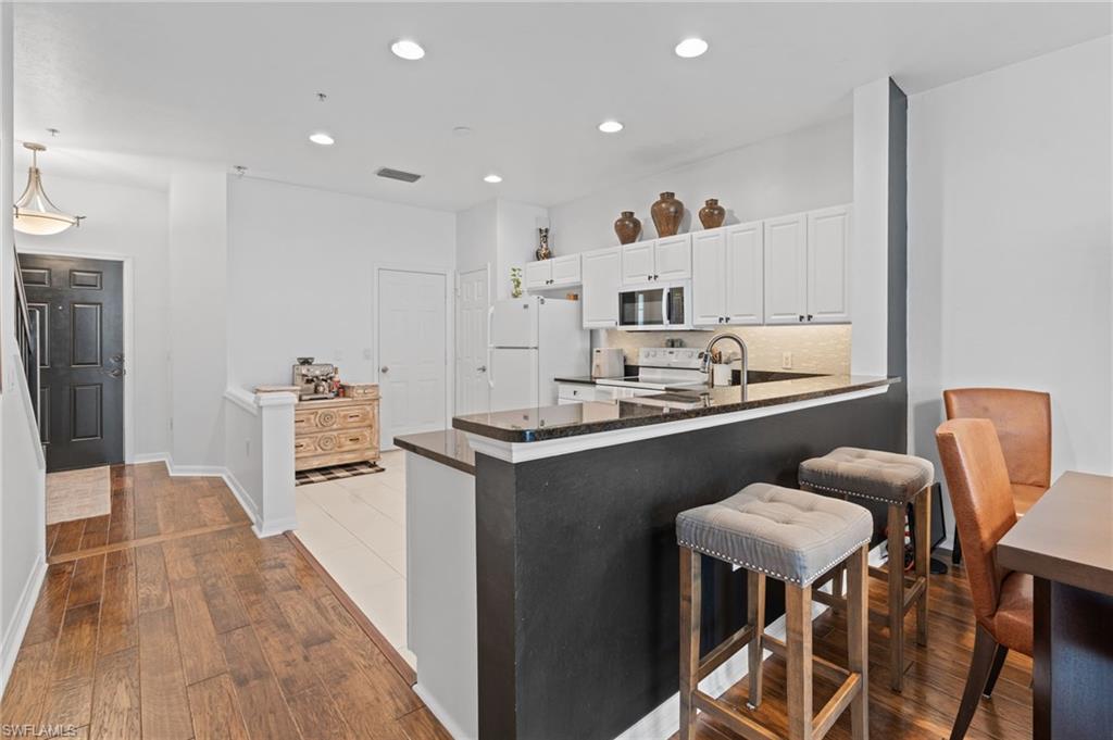 941 Hampton Circle, Unit 109 Naples, FL 34105 - Photo 1 of 27 a kitchen with stainless steel appliances granite countertop a sink a stove a refrigerator and island with wooden floor