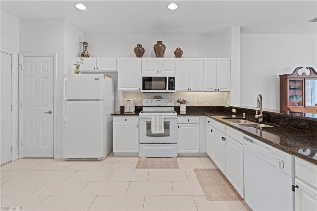 941 Hampton Circle, Unit 109 Naples, FL 34105 - Photo 14 of 27 a kitchen with white cabinets and white appliances