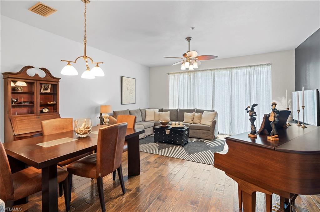 941 Hampton Circle, Unit 109 Naples, FL 34105 - Photo 3 of 27 a living room with furniture a chandelier and a dining table