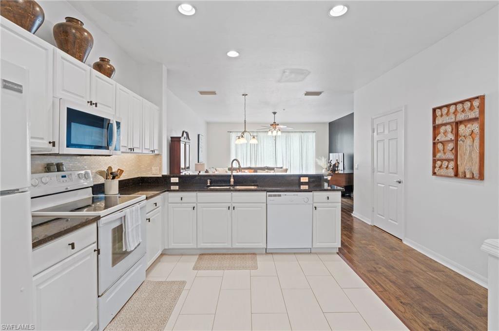 941 Hampton Circle, Unit 109 Naples, FL 34105 - Photo 7 of 27 a large white kitchen with a sink and dishwasher a stove top oven with wooden floor