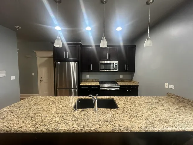 a kitchen with stainless steel appliances granite countertop a sink stove and refrigerator