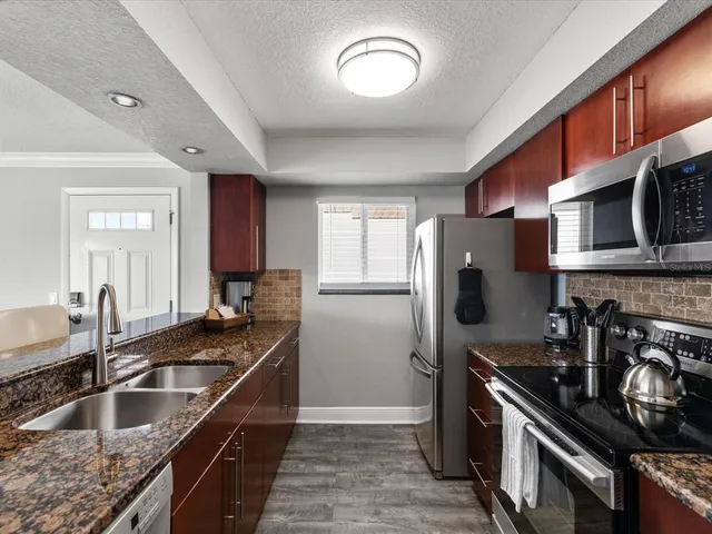 a kitchen with granite countertop a sink stove and refrigerator