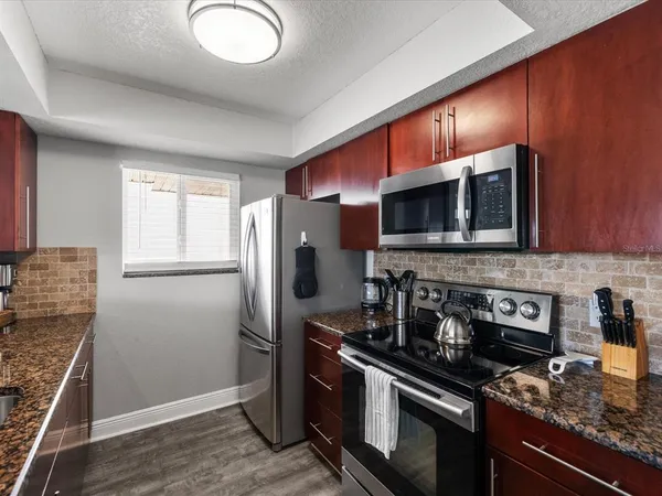 a kitchen with stainless steel appliances granite countertop a stove a microwave and a refrigerator