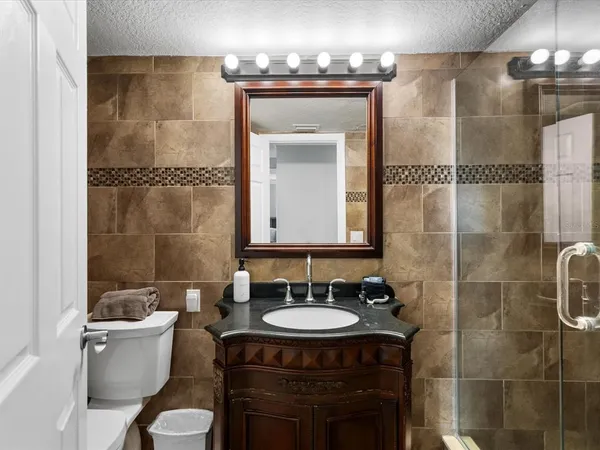 a bathroom with a granite countertop sink toilet a mirror and shower