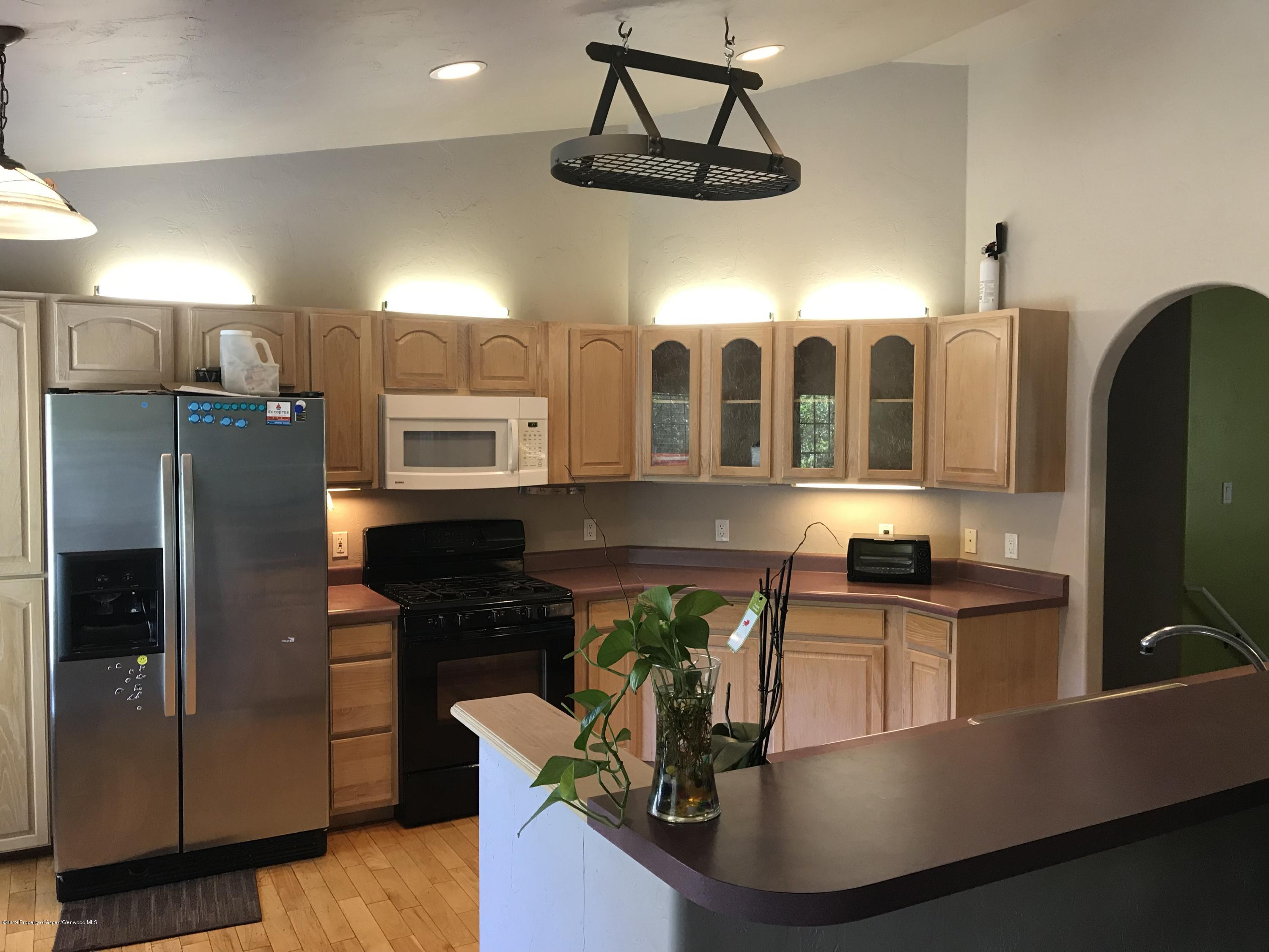 525 Birch Court Rifle, CO 81650 - Photo 5 of 17 a kitchen with stainless steel appliances granite countertop a refrigerator a stove and a sink with wooden floor