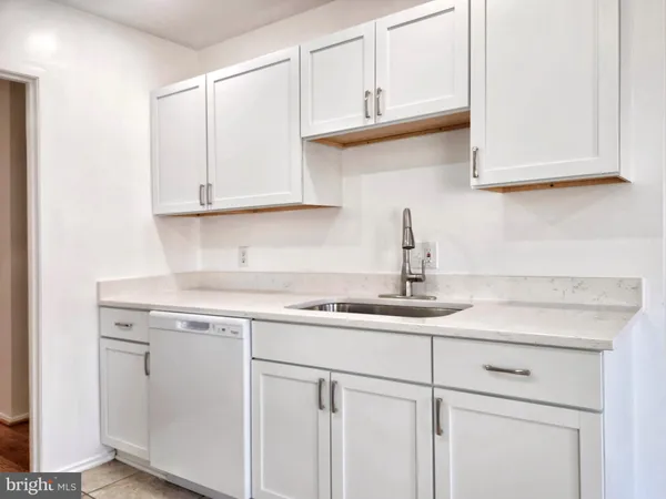 a kitchen with white cabinets and window