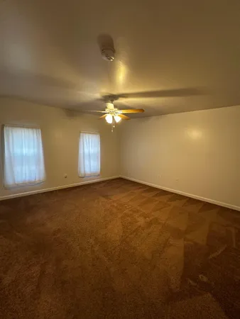 a view of an empty room with a chandelier fan
