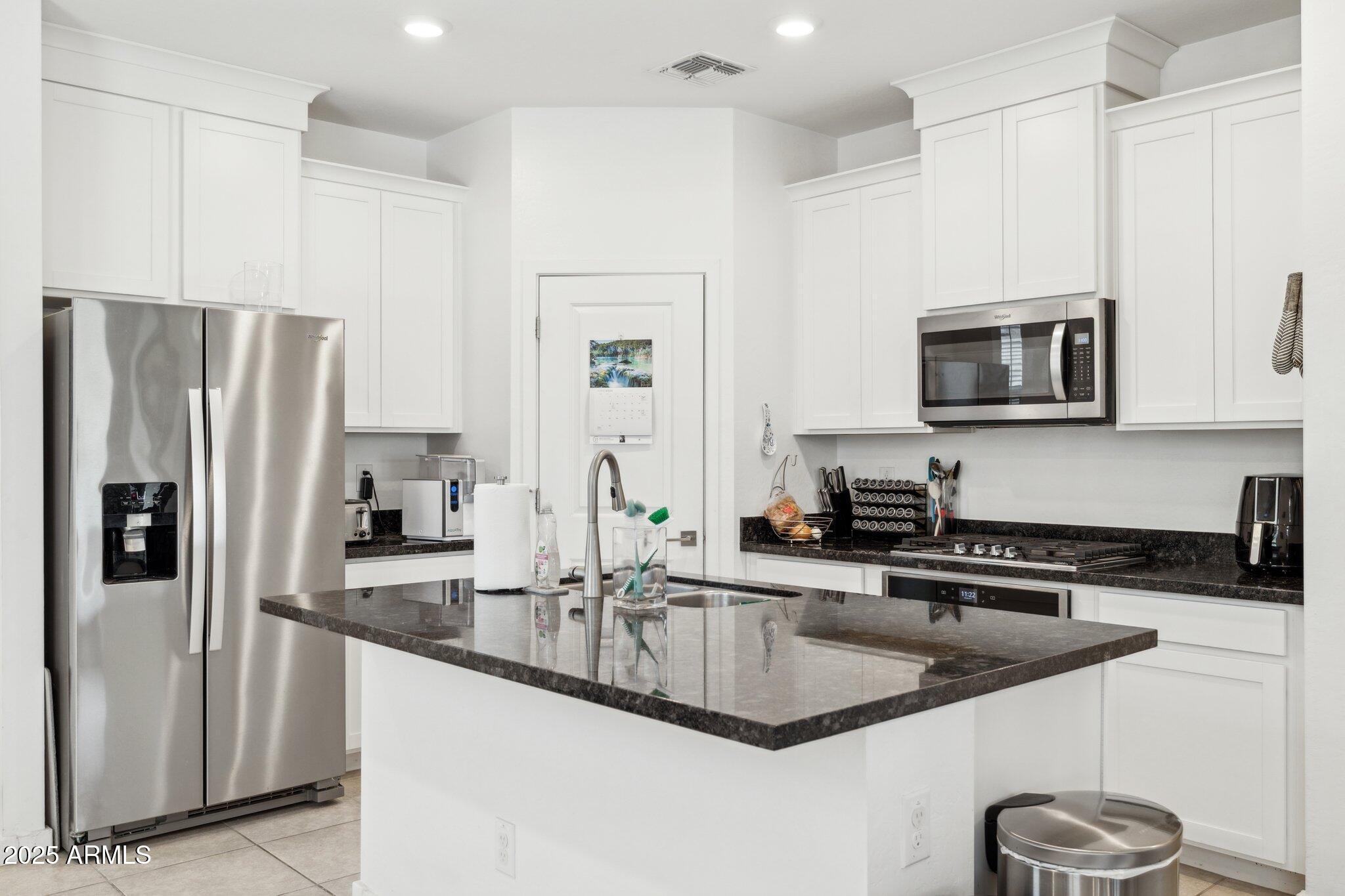 14360 West Pershing Street Surprise, AZ 85379 - Photo 4 of 24 a kitchen with stainless steel appliances granite countertop a sink a microwave a refrigerator and white cabinets