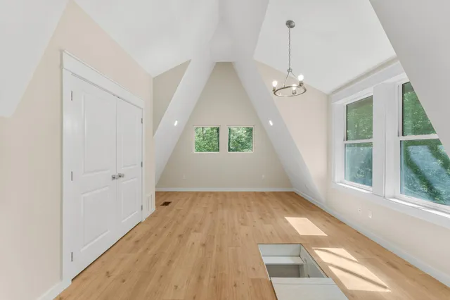 an empty room with wooden floor exposed radiator and windows