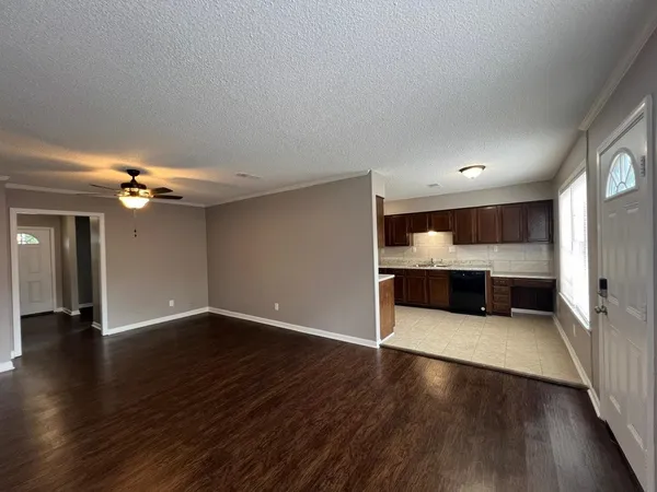 an empty room with wooden floor fireplace and windows