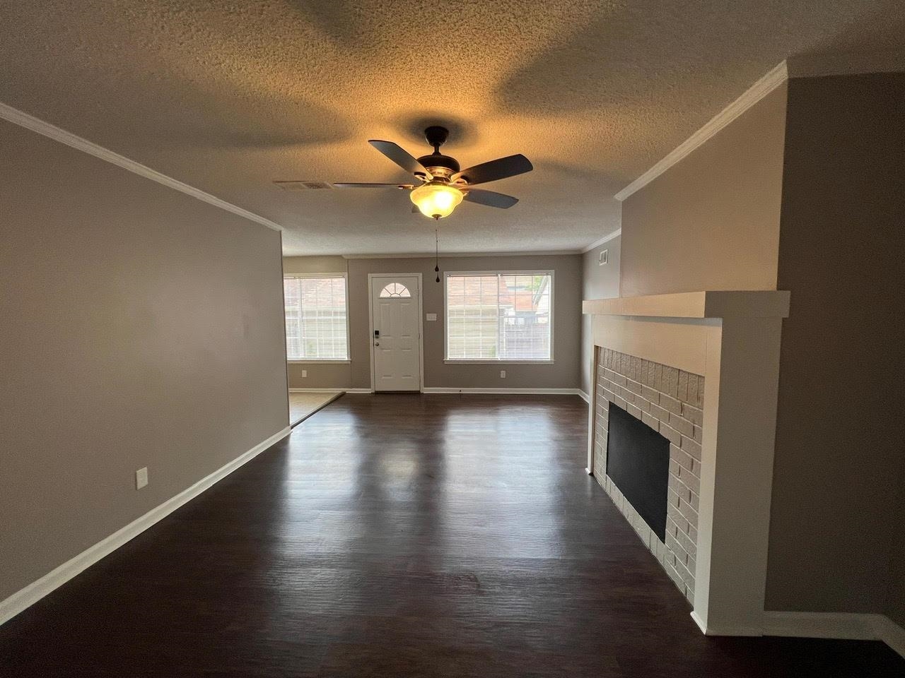 5995 Lofty Oak Road, Unit 5995 Memphis, TN 38115 - Photo 15 of 20 Unfurnished living room with ceiling fan, a fireplace, dark wood-type flooring, and ornamental molding