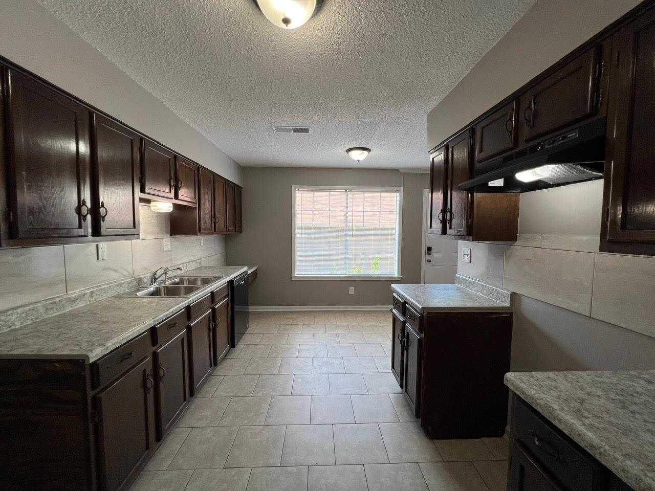 5995 Lofty Oak Road, Unit 5995 Memphis, TN 38115 - Photo 3 of 20 Kitchen with a textured ceiling, dark brown cabinets, decorative backsplash, and light tile patterned floors