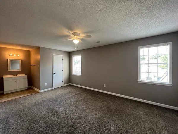 a view of an empty room with window and chandelier fan