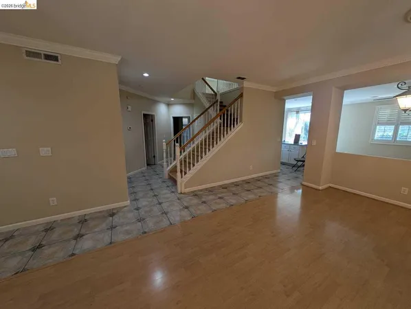 a view of an empty room with stairs and wooden floor