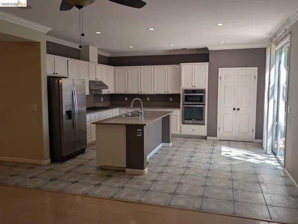a kitchen with kitchen island stainless steel appliances a sink a counter top space cabinets and a window