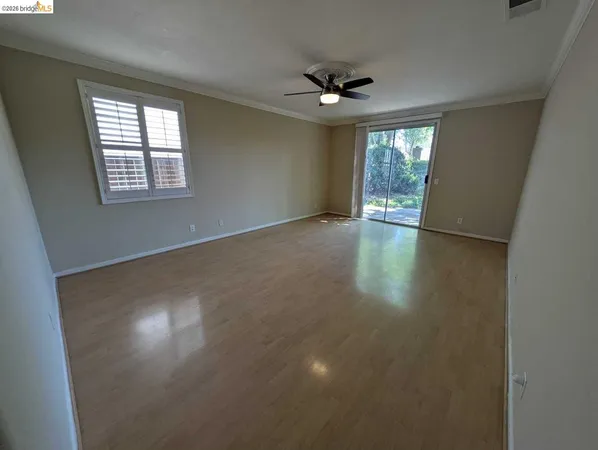 a view of an empty room with a window and wooden floor