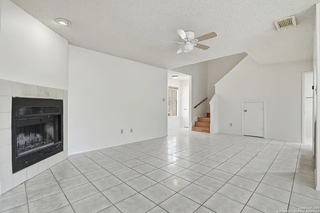a view of an empty room with a fireplace and a chandelier fan