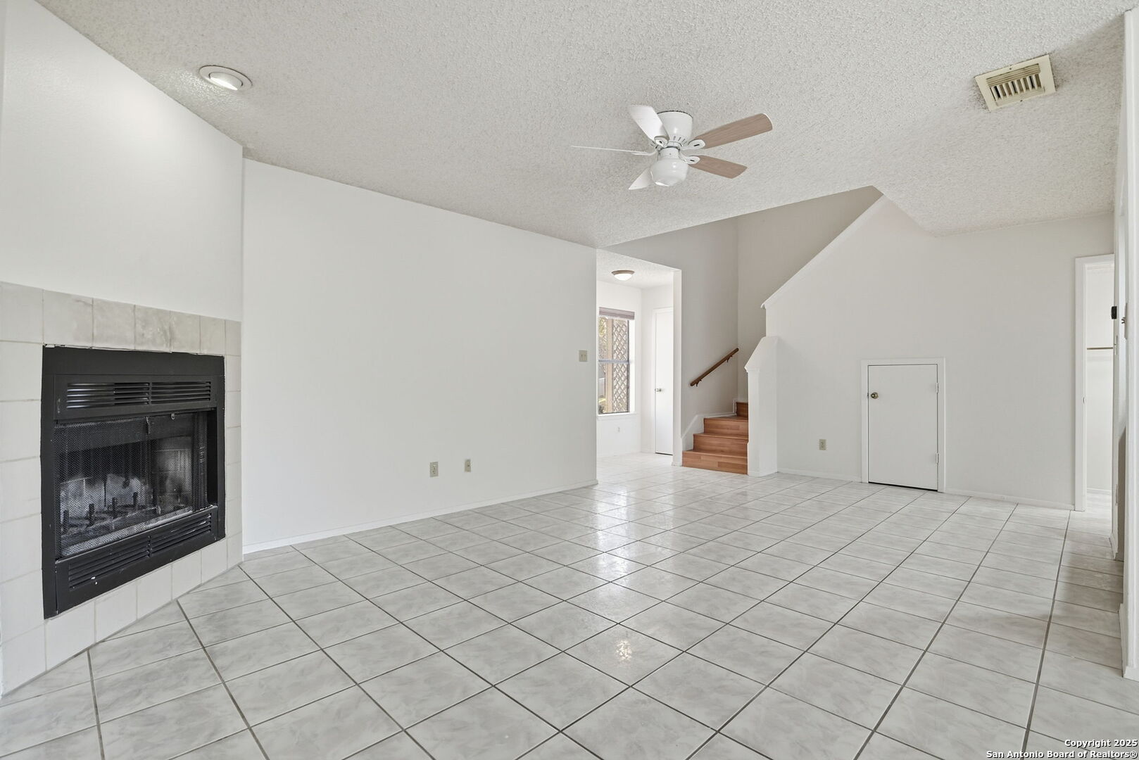 8702 Stream Circle San Antonio, TX 78250 - Photo 5 of 18 a view of an empty room with a fireplace and a chandelier fan