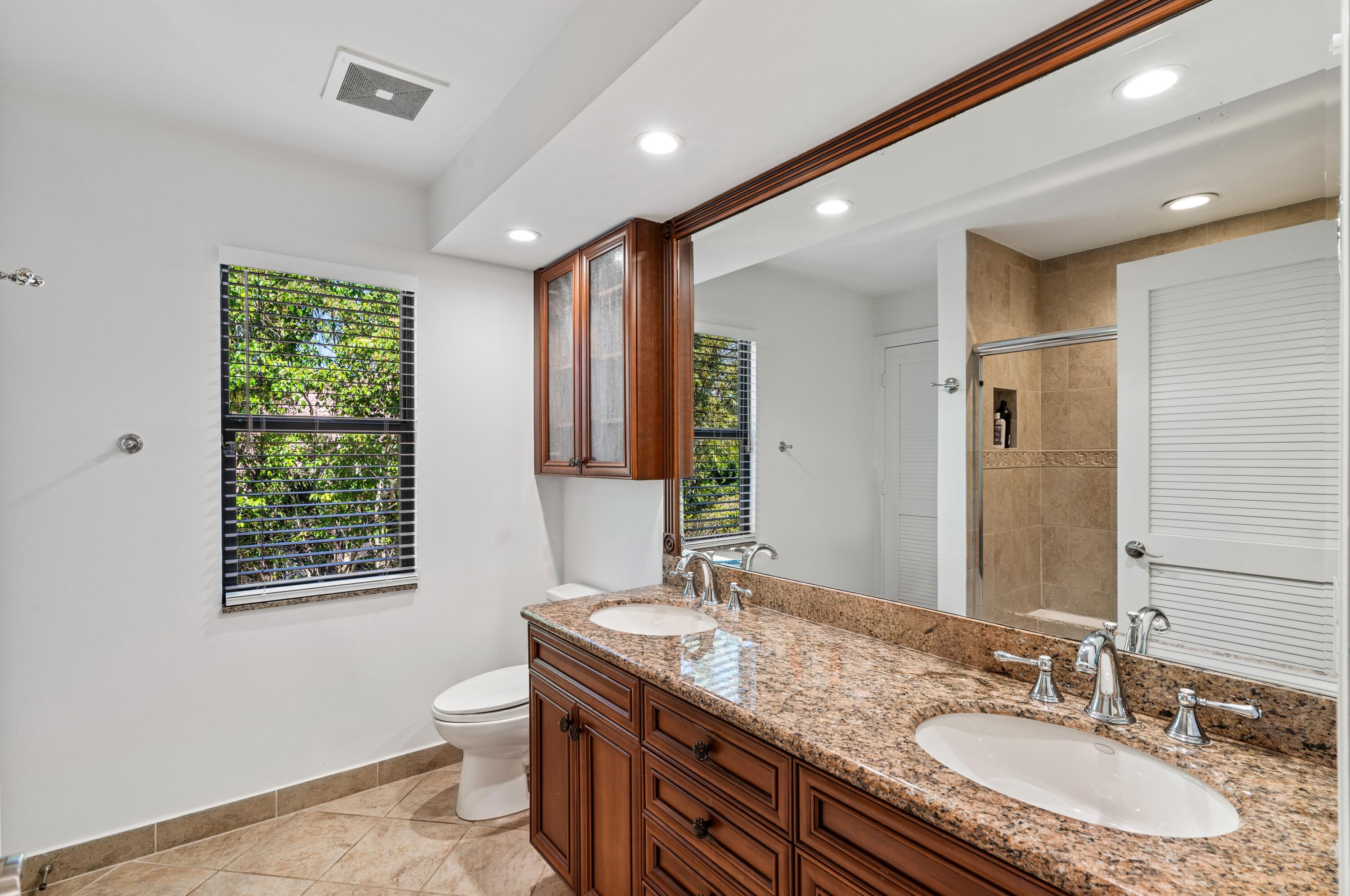 3098 Northwest 60th Street Boca Raton, FL 33496 - Photo 22 of 30 a bathroom with a granite countertop sink a toilet a mirror a vanity and window